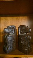 Pair of carved wooden Native Eagle style bookends viewed from front showing detailed eagle heads and geometric patterns.