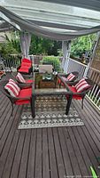 Full patio set on deck showing the table, chairs with cushions and pillows, outdoor rug and centerpiece on table