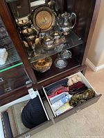 Full view of upper and lower cabinet with silver plated items and drawers with linens.