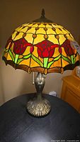 Lamp assembled and lit, showing overall shape, stained glass shade and base.