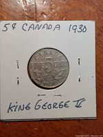Front side of the coin mounted in cardboard holder with handwritten label showing year and King George V reference.