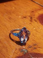 Close-up photo of marquise-shaped faceted purple gemstone set in sterling silver ring with detailed band.