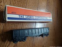 Black 6032 Lionel Lines gondola railcar with original box labeled 'The Lionel Corporation New York Chicago'. Gondola is black with white lettering.