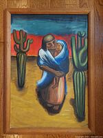 Front view of the oil painting showing a Navajo woman carrying a child between two cacti with a colorful sunset sky, wood framed.
