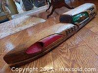 Side view of the wooden Raven sculpture showing red and black painted accents and the articulated jaw.