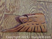 Wood carved eagle sculpture showing side profile on wood floor background.