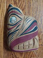 Front and angled views of vintage wood carved and painted bear head sculpture by Stan Joseph with mother of pearl eye detail against wood floor background.