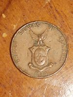 Close-up photo of one side of the 1944 US wartime Philippines One Centavo coin showing United States of America around the edge, an eagle on top of the Philippines coat of arms, and the date 1944 at the bottom.