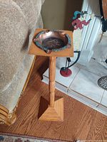Side view of wooden pedestal ashtray showing square tapered base and rounded column shaft topped with a hammered copper ashtray.