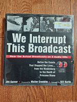 Front cover of the hardcover book 'We Interrupt This Broadcast' showing title text and promotional information about 2 included audio CDs.