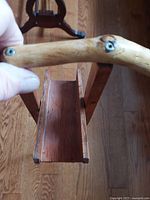 Close-up of wooden handle of the folk art bathroom cane, showing natural wood grain and attached screws.