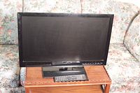 Front view of the ONN 23-inch LED TV, showing the screen and remote on the table.