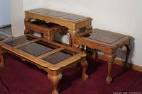 Full view showing one coffee table, two end tables, and one sofa table in medium-toned wood with glass tops, displayed on red carpet.