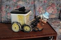 Horse and carriage cookie jar front and side view showing the horse with blue hat, yellow carriage with black wheels, and black removable lid with horse figure.