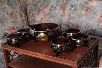 Full view of one large glass bowl surrounded by six smaller matching bowls on wooden tray