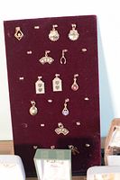 Velvet display board showing 12 gold-tone pendants and charms in various shapes