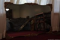 Full view of the large rectangular mirror showing the frame with gold decorative accents and the reflective surface.