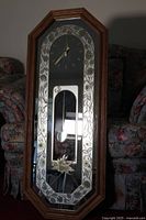 Full view of tall mirror clock showing wooden trim, floral mirrored design, clock face and pendulum