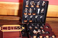 Chess pieces arranged inside their storage case and the foldable chess board placed alongside.