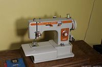 Front and side view of Brother Sewing Machine model 1681 showing orange control panel and off-white body.