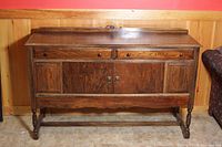 Sideboard front view showing wood grain, two drawers on top, two cabinet doors below, and turned legs.