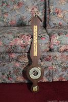 Complete view of the wooden weather barometer on floral couch background