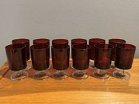 Front view showing 12 ruby red cordial sherry glasses in a row on clear short stems