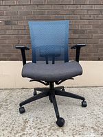 Front view of chair showing mesh back, upholstered seat, adjustable arms and five-star base with casters