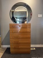 Front view of teak 5-drawer dresser with round mirror on top
