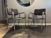 Front view of both chairs side by side showing chrome frames and black vinyl seats.