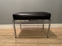 Footstool ottoman side view showing black cushion and chrome steel legs