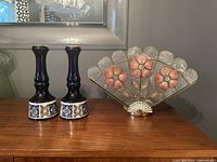 Full view of two blue and white ceramic candle holders next to a decorative fan-shaped floral table lamp.