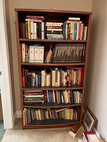 Tall wooden bookshelf filled with various books to demonstrate shelf capacity.