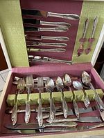 Cutlery set displayed inside original box with forks, knives and spoons organized in compartments with fabric lining.