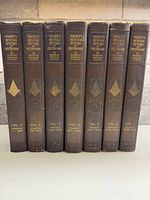 Spines of all seven leather-bound volumes showing titles, volume numbers and page ranges