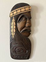 Front view of the carved wooden Indigenous art wall hanging showing profile of native figure and animal motif.
