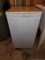 Front view of closed white Danby Designer mini bar fridge with cream top, showing minor wear.