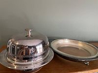 Two silver-tone covered butter or cheese dishes with domed lids and decorative details