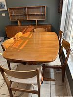 Front angle showing teak dining table with four chairs and hutch behind