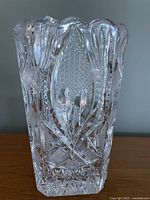 Cut crystal vase with detailed geometric cuts and textured leaf pattern.