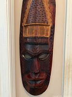 Close-up of carved wooden mask showing detailed facial features and forehead design