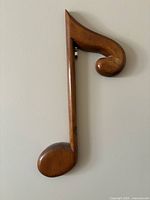 Wooden eighth note wall decoration with polished medium brown finish, mounted on wall.