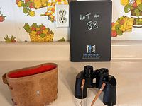 Baker Deluxe binoculars paired with original brown leather case on kitchen counter, showing condition and included items