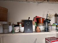 Shelf with plant pots, ceramic containers, glass jars, and small garden tools.