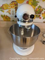 Front view of white KitchenAid stand mixer with stainless steel bowl in place on countertop.