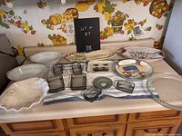 Countertop display of various kitchen serving dishes and small glass bowls and plates, showing detail and variety of items in the lot.