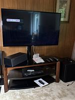 Full TV setup showing LG television mounted on TV stand along with speakers, remotes, and media player.