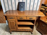 Wooden vintage sideboard with three drawers, a cabinet, two shelves, and extendable surface in retracted position.