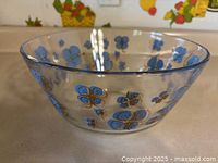 Clear glass bowl shown from side angle highlighting blue clover design on outside and inside rim.