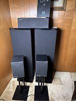 Overall view of all five speakers and two stands against wood-paneled wall